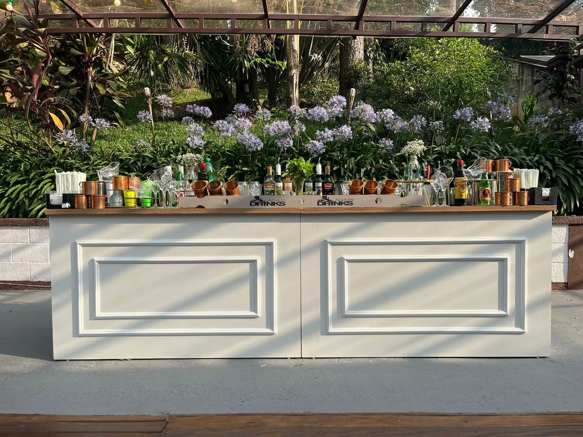 Bar da Agari montado ao ar livre, com vidraria e garrafas no balcão